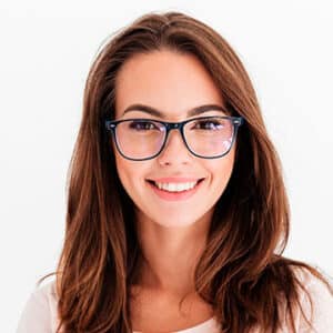 A young woman with long brown hair and black-framed glasses smiles warmly at the camera. She is wearing a light-colored top, and has a bright, clear complexion. The background is plain white, highlighting her face and features.