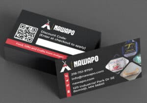 A stack of business cards for "NAWAPO" showcases their graphic design services with a prominent QR code, discount code, contact details, and images of products they offer. The card lists the email, website, phone number, and physical address: 1211 Industrial Park Dr SE, Bemidji, MN 56601.