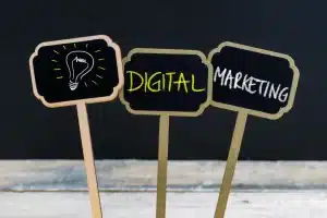 Three miniature blackboard signs on sticks are displayed. The first has a drawing of a light bulb, representing an idea. The second reads "DIGITAL" in yellow chalk, and the third reads "MARKETING SERVICES" in white chalk, suggesting the concept of digital marketing services.