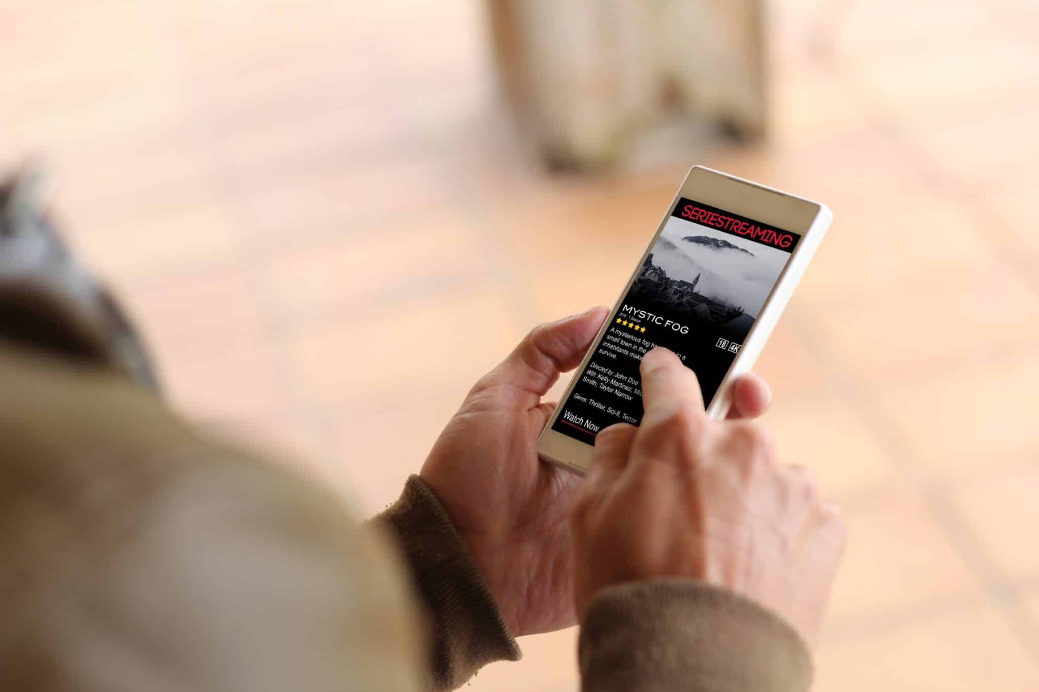 A person holds a smartphone displaying a video streaming app, where the title "Mystic Fog" and star ratings are prominently featured, building customer trust. The blurred background keeps the focus on the phone's screen, emphasizing a sleek web design that enhances user experience.