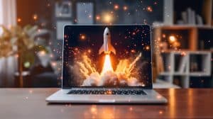 A laptop on a wooden table displays a rocket launching through clouds on its screen. Sparks and glowing particles appear around the laptop, creating a dynamic and inspirational scene. The background is softly blurred with room decor.