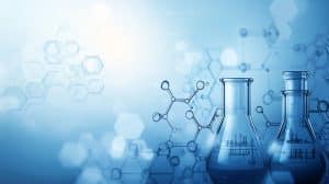 Two glass beakers filled with a blue liquid are set against a background of chemical formulas and hexagonal patterns, symbolizing a scientific or laboratory setting. The image has a blue color scheme, evoking a sense of modern science and experimentation.