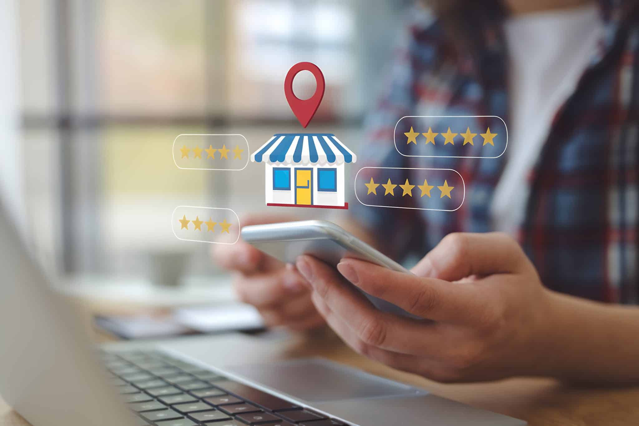 A person holds a smartphone near a laptop, with digital illustrations hovering. Icons include a store with a location pin and several star ratings, capturing the essence of online shopping or business reviews—perfect for webmasters keen on optimizing website design.