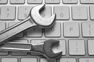 Two metal wrenches are placed diagonally on a computer keyboard, representing website maintenance and the importance of keeping your site running smoothly in 2025.