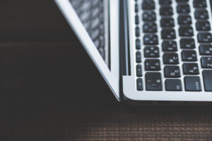 A close-up view of a partially open laptop on a dark wooden surface, showing the keyboard and part of the screen.