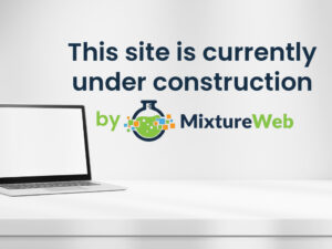 A laptop on a white desk with the text "This site is currently under construction by MixtureWeb" and a flask logo on a light background.