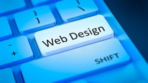 A close-up of a computer keyboard with a glowing "Web Design" key, symbolizing the power of Online Presence, where Enter would usually be. The Shift key is nearby, and the image is tinted blue.