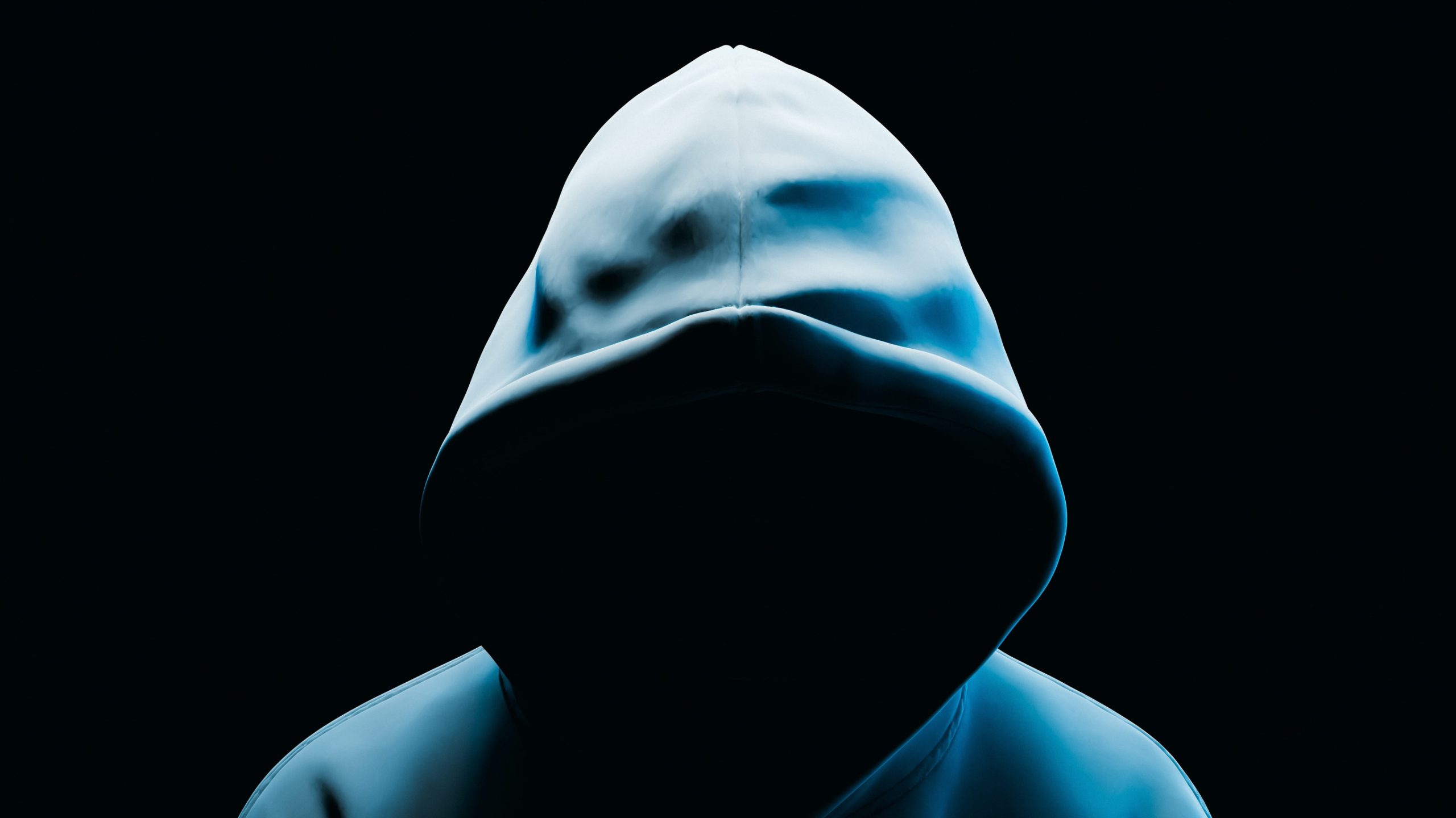 A person wearing a hoodie with their face completely obscured by deep shadow, symbolizing the threat of a hacked website.